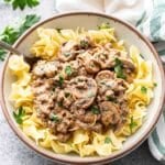Ground Beef Stroganoff on top of egg noodles in a white bowl.