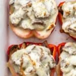 Cheesesteak Stuffed Peppers topped with melted provolone cheese in a white baking dish.