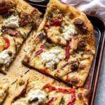 Pesto chicken pizza on a sheet pan cut into square slices.