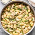 Creamy Gnocchi with Asparagus, peas, chicken, and parmesan cheese in a skillet.