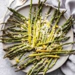 Lemon parmesan roasted asparagus on a gray plate with two forks beside the plate.