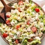 Chicken Caesar Pasta Salad in a white serving bowl with wooden spoons.
