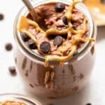 Chocolate Peanut Butter Overnight Oats in a jar with a spoon in it. They're topped with peanut butter and chocolate chips.