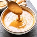 Bowl of peanut sauce with a spoon scooping some out of it.