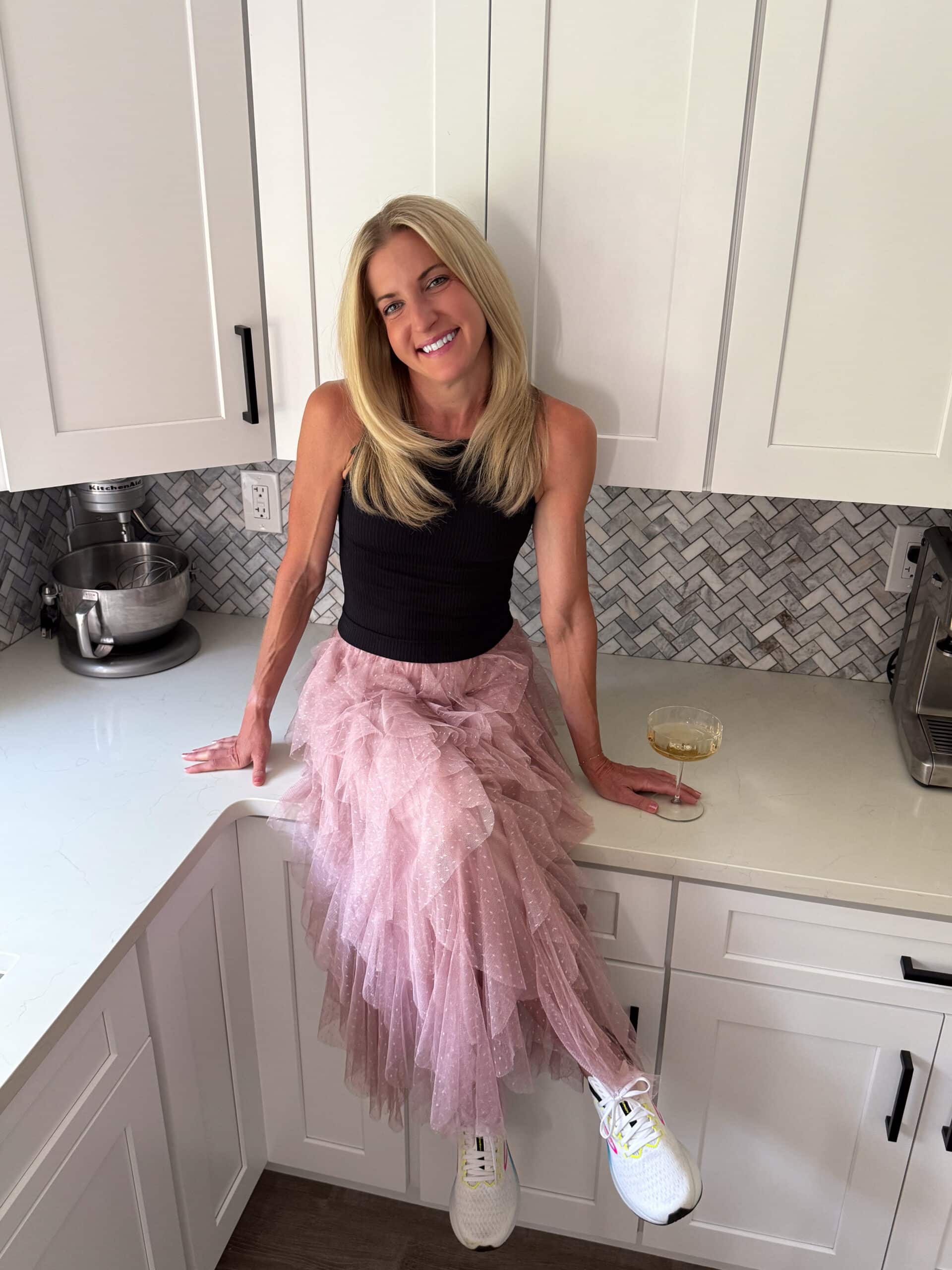 Danae sitting on kitchen counter with a glass of prosecco.