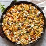 Greek chicken and orzo topped with feta and olives in a skillet.