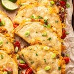 Crispy Baked Chicken Tacos layered on top of each other with lime wedges next to them.