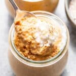A spoon scooping pumpkin chia pudding out of a jar.