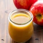 Apple Cider Vinaigrette in a jar with two apples behind it.