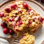 A piece of cranberry orange baked oatmeal on a white plate with a fork.