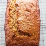 A loaf of banana bread on a wire cooling rack.
