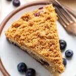 A slice of blueberry coffee cake on a white plate.
