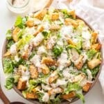 Caesar salad topped with croutons, parmesan cheese, and dressing.