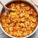 Cajun shrimp and rice in a skillet with a wooden serving spoon.