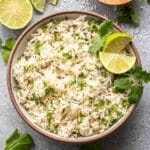 A bowl of cilantro lime rice with lime wedges for garnish.