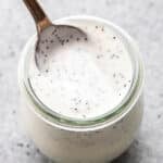 Greek yogurt poppy seed dressing in a jar with a spoon in it.