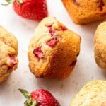 Strawberry muffins with strawberries next to them.