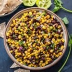 Black bean salsa in a white bowl with chips next to it.