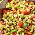Chicken pesto pasta salad with tomatoes in a white serving bowl.