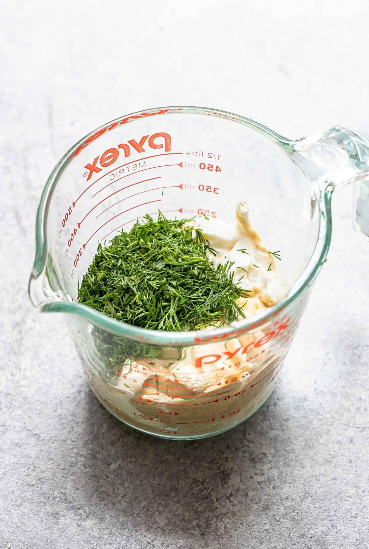 Ingredients for dill dressing in a glass measuring cup.
