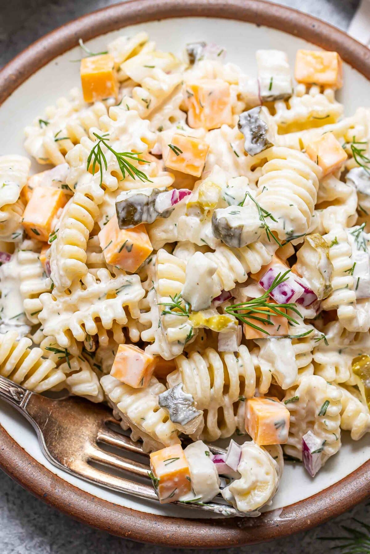 Dill pickle pasta salad on a white plate with a fork.
