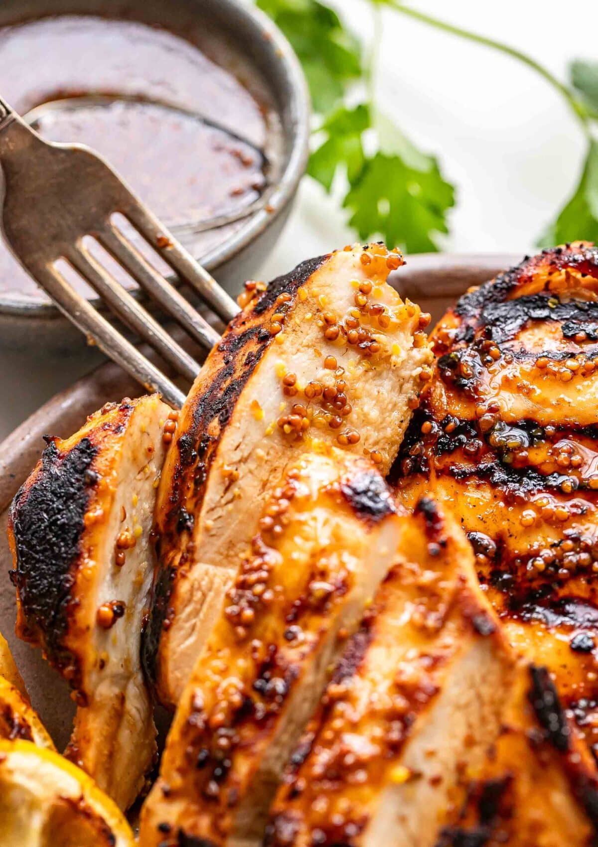 Fork picking up a slice of honey mustard grilled chicken.