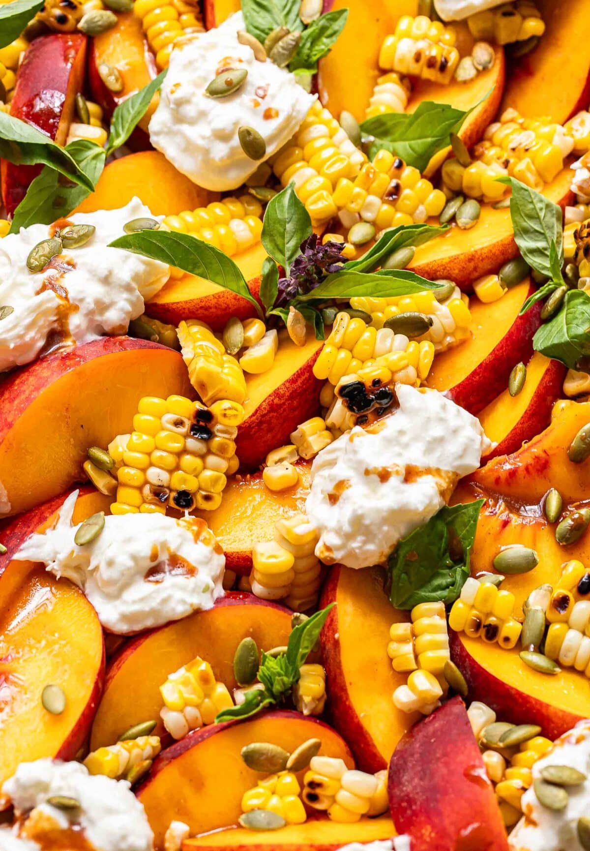 Sliced peaches, burrata, corn, basil leaves, and pepitas drizzled with balsamic vinaigrette.