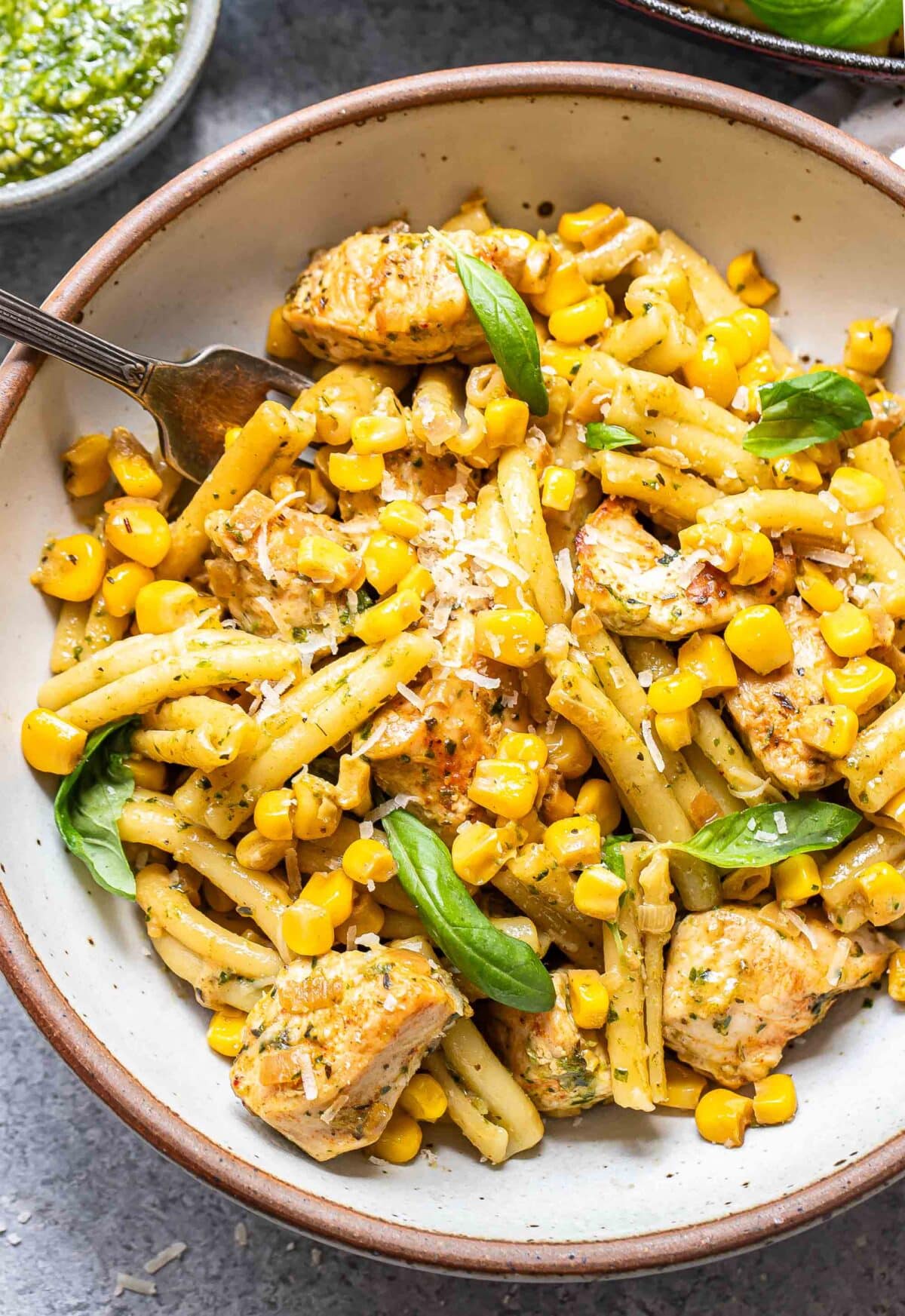 Chicken corn pasta in a white bowl with a fork.