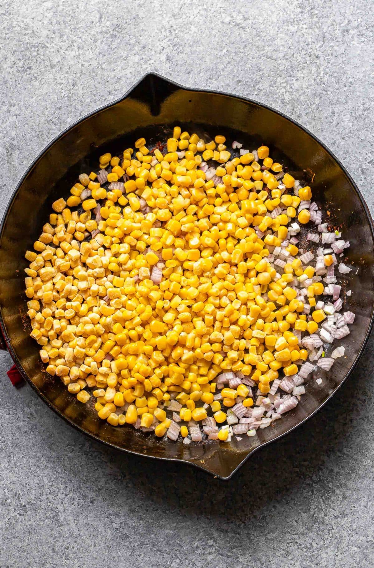 Corn and shallots in a skillet.