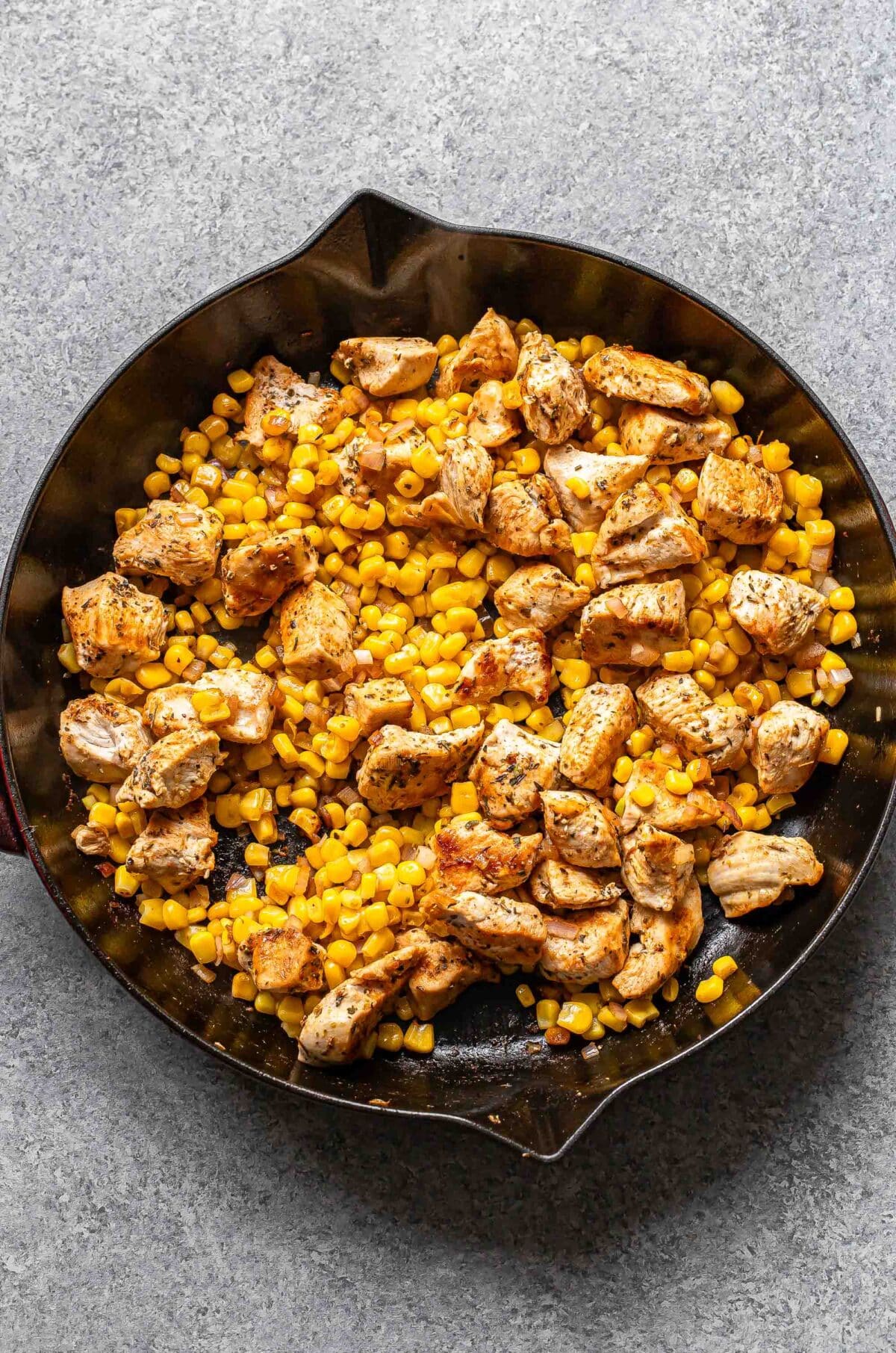 Sauteed corn and chicken in a skillet.