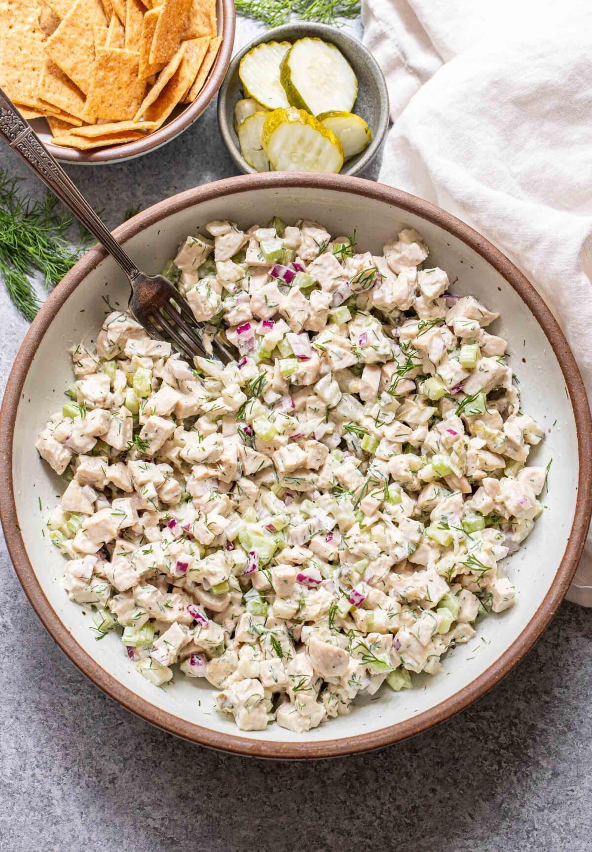 Dill pickle chicken salad in a white bowl with a fork in it.