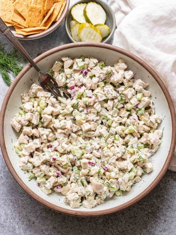 Dill pickle chicken salad in a white bowl with a fork in it.