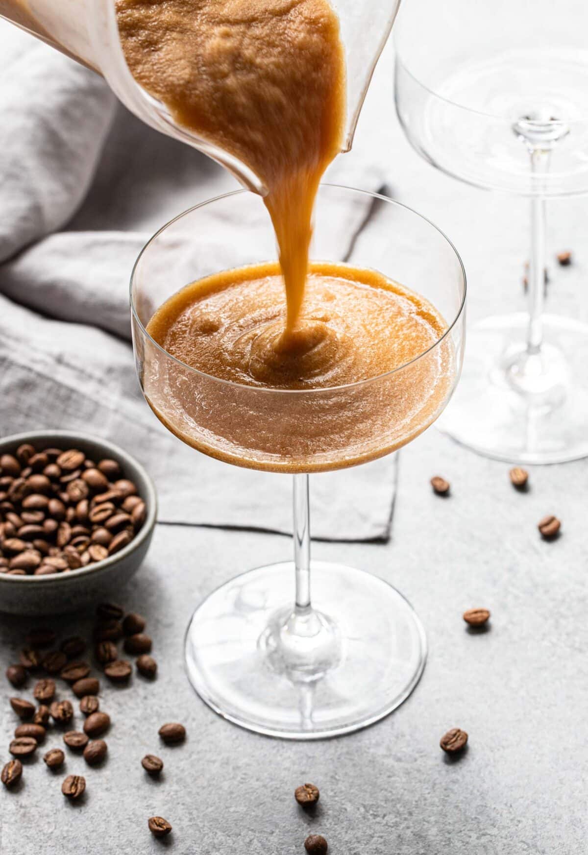 Frozen espresso martini being poured into a stemmed cocktail glass.