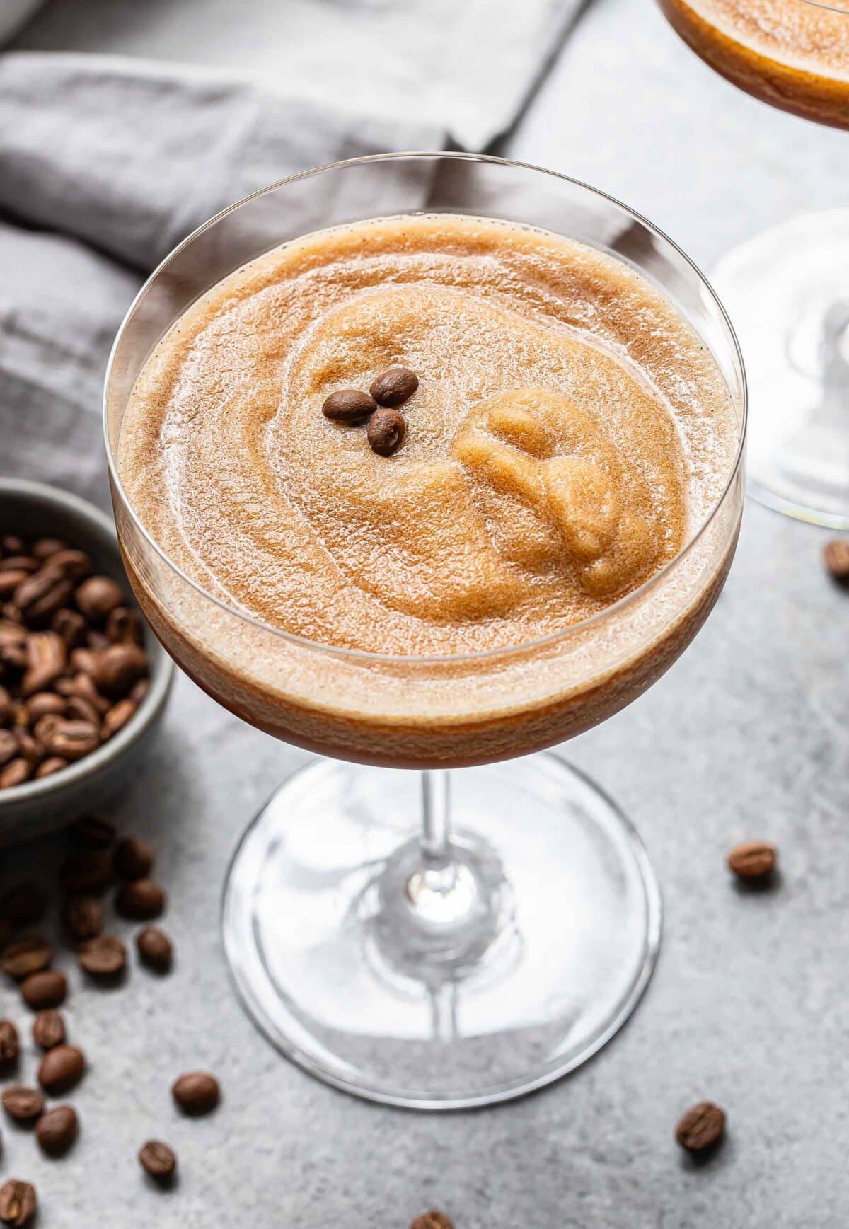 A frozen espresso martini with 3 coffee beans on top for garnish.