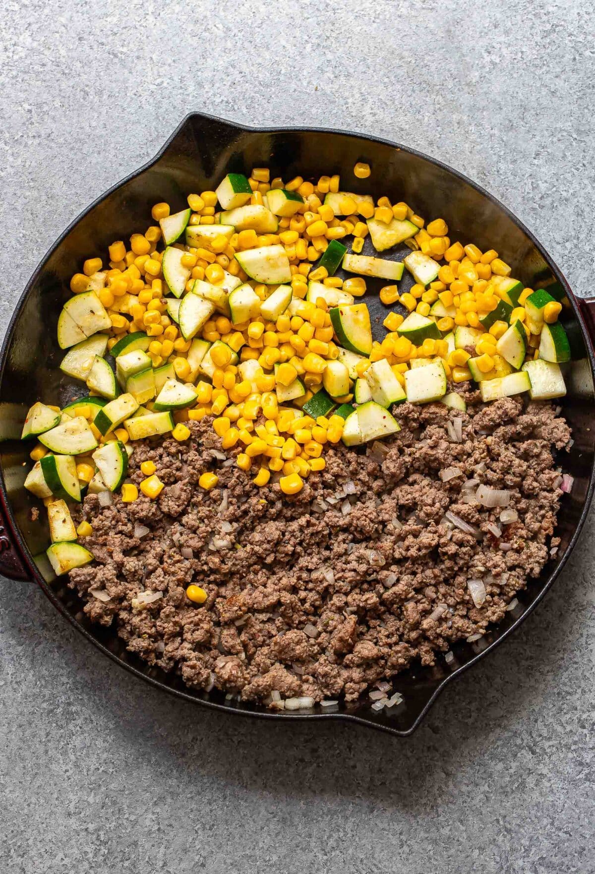 Ground beef, zucchini and corn in a skillet.