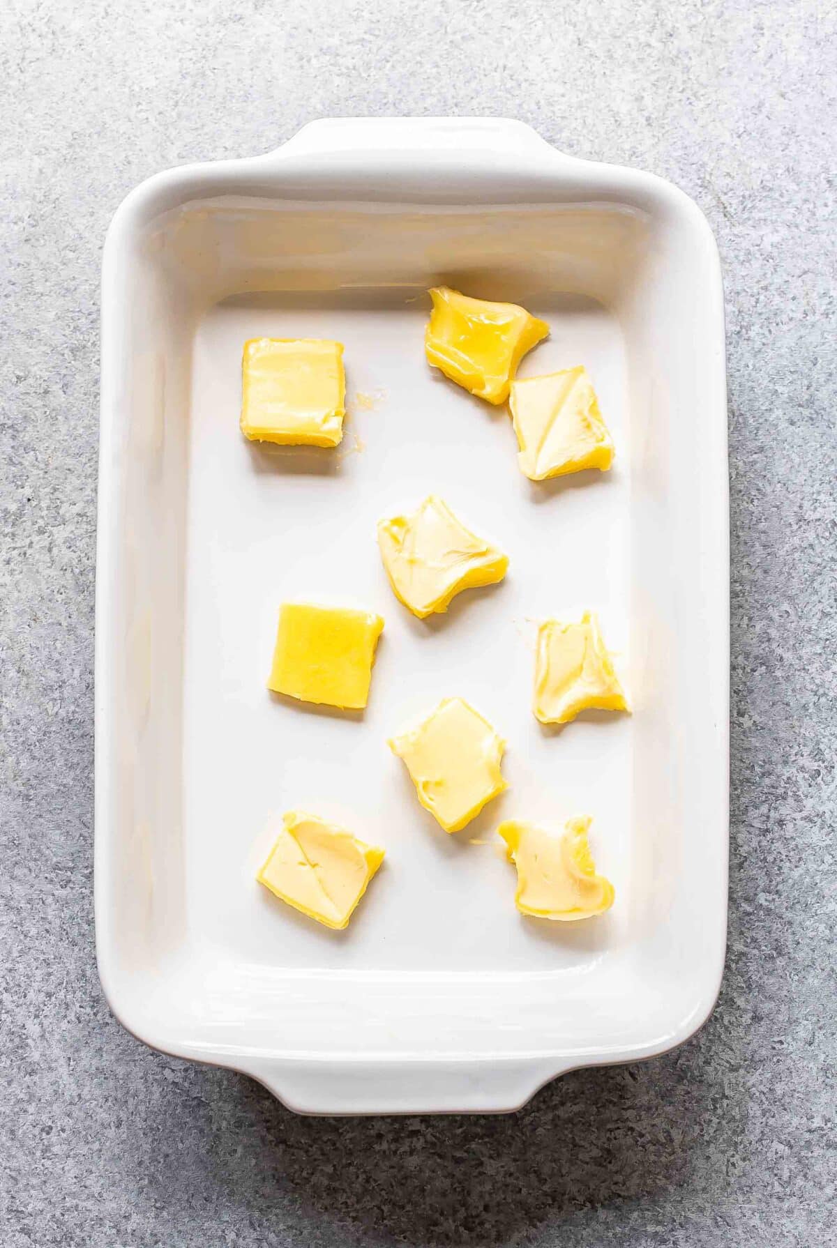 Pats of butter in a rectangular white baking dish.