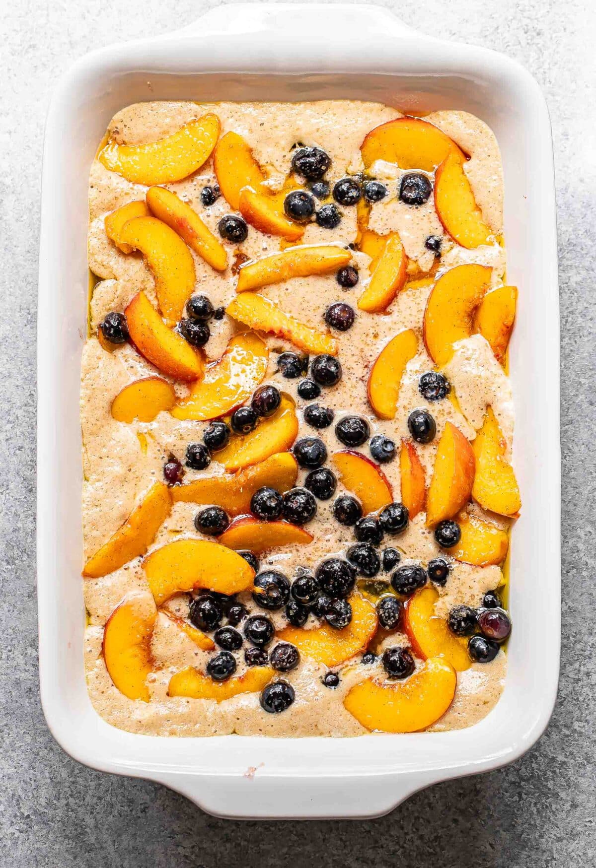 Peach blueberry cobbler in a rectangular baking dish before it's been baked.