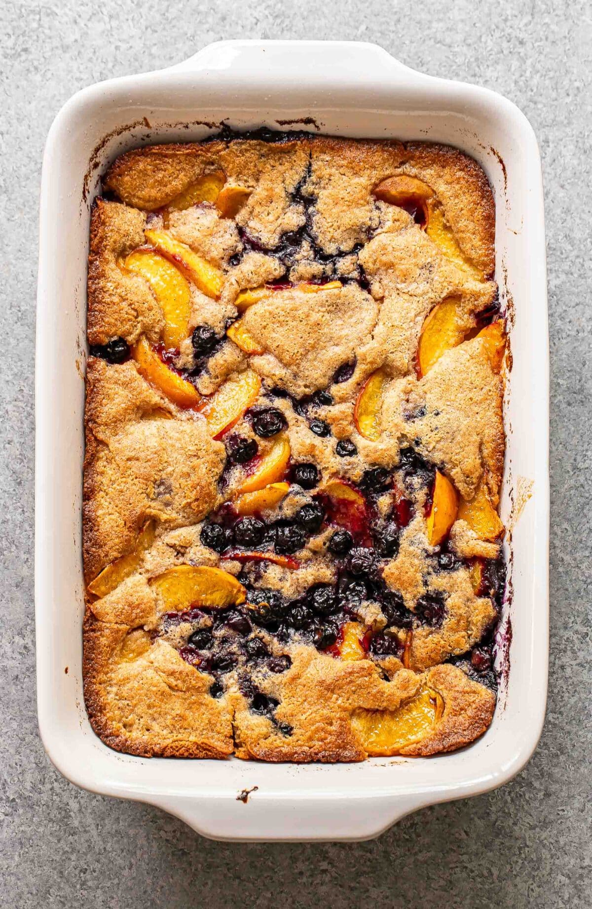 Peach blueberry cobbler in a white rectangular baking dish.
