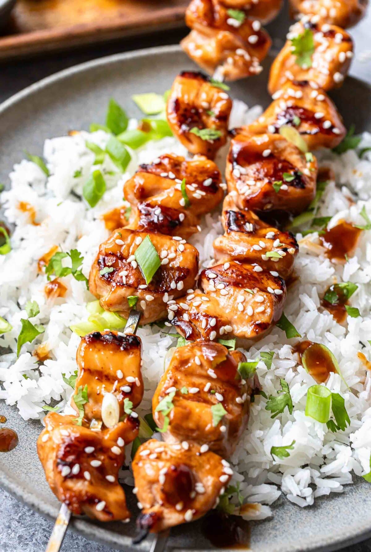 Two teriyaki chicken skewers on top of white rice.