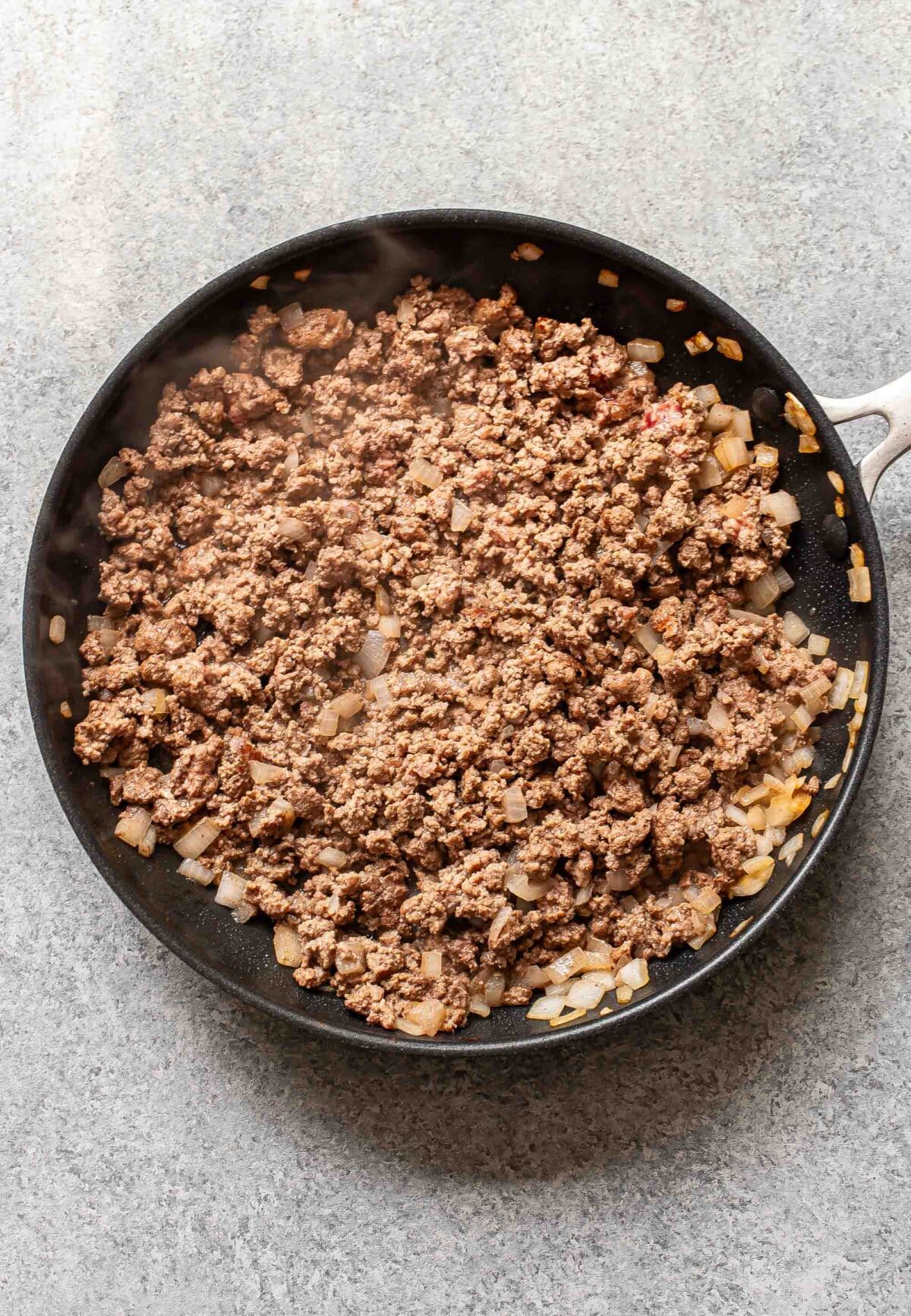 Crumbled ground beef and onions in a skillet.
