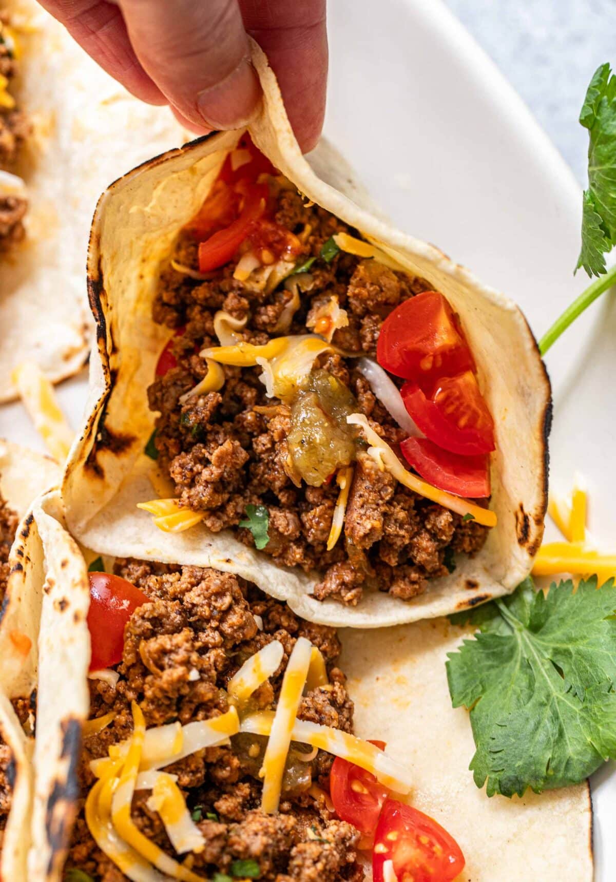 Hand picking up a ground beef taco.