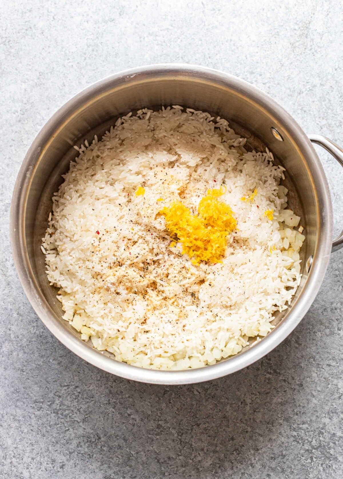 Rice with lemon zest on top before it's been cooked.