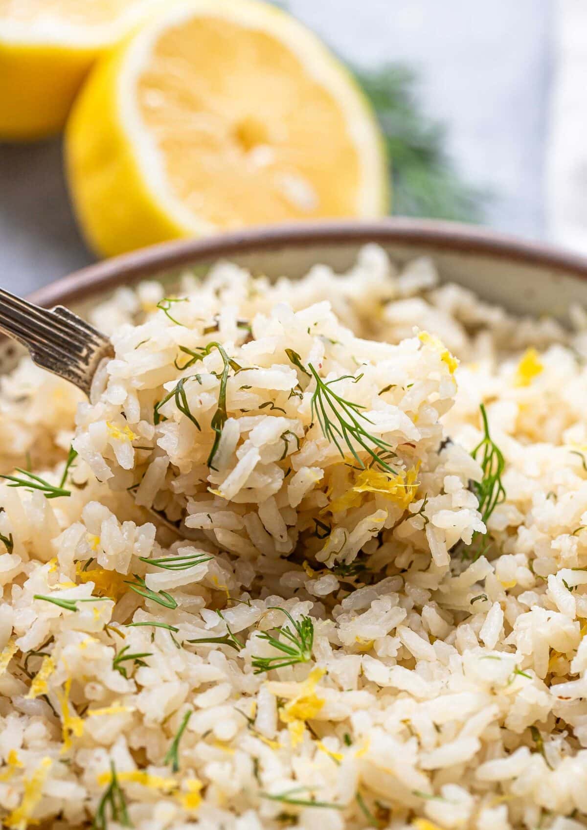 Spoon lifting up a scoop of lemon rice with dill.