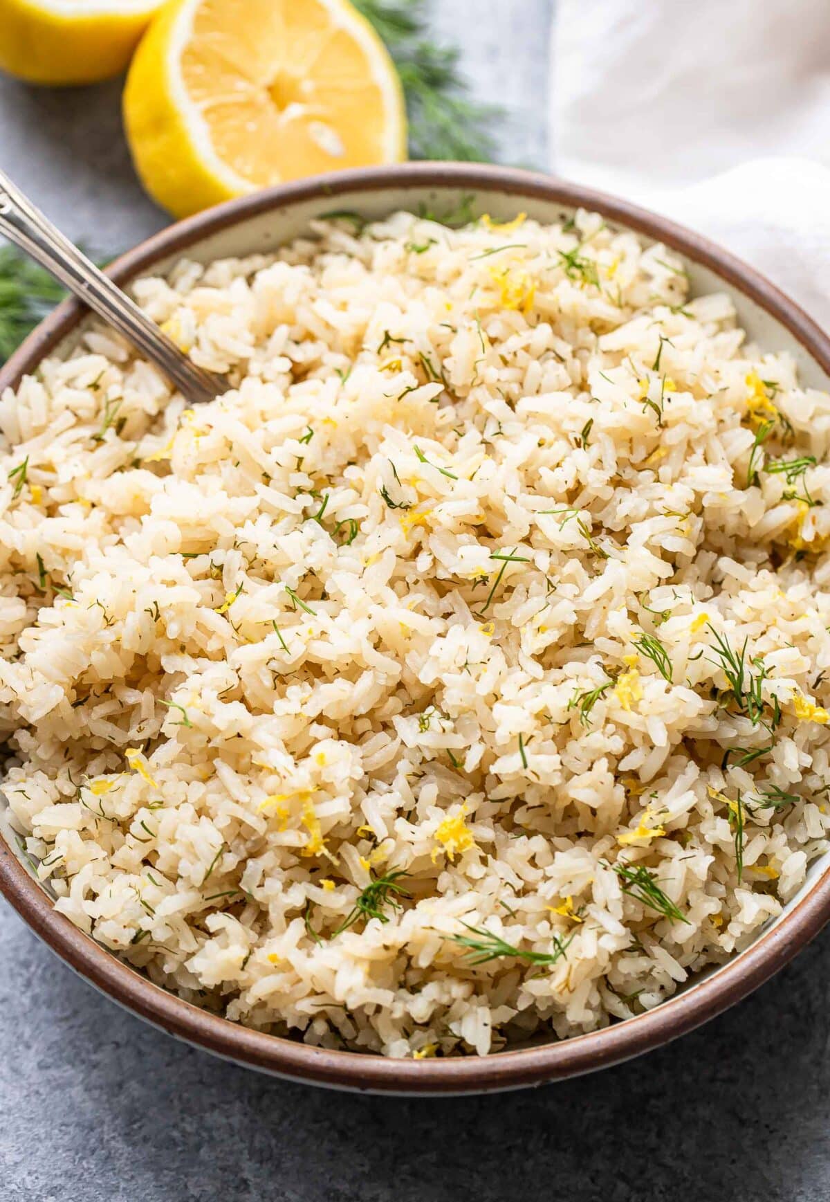Lemon dill rice in a white serving bowl with a spoon.