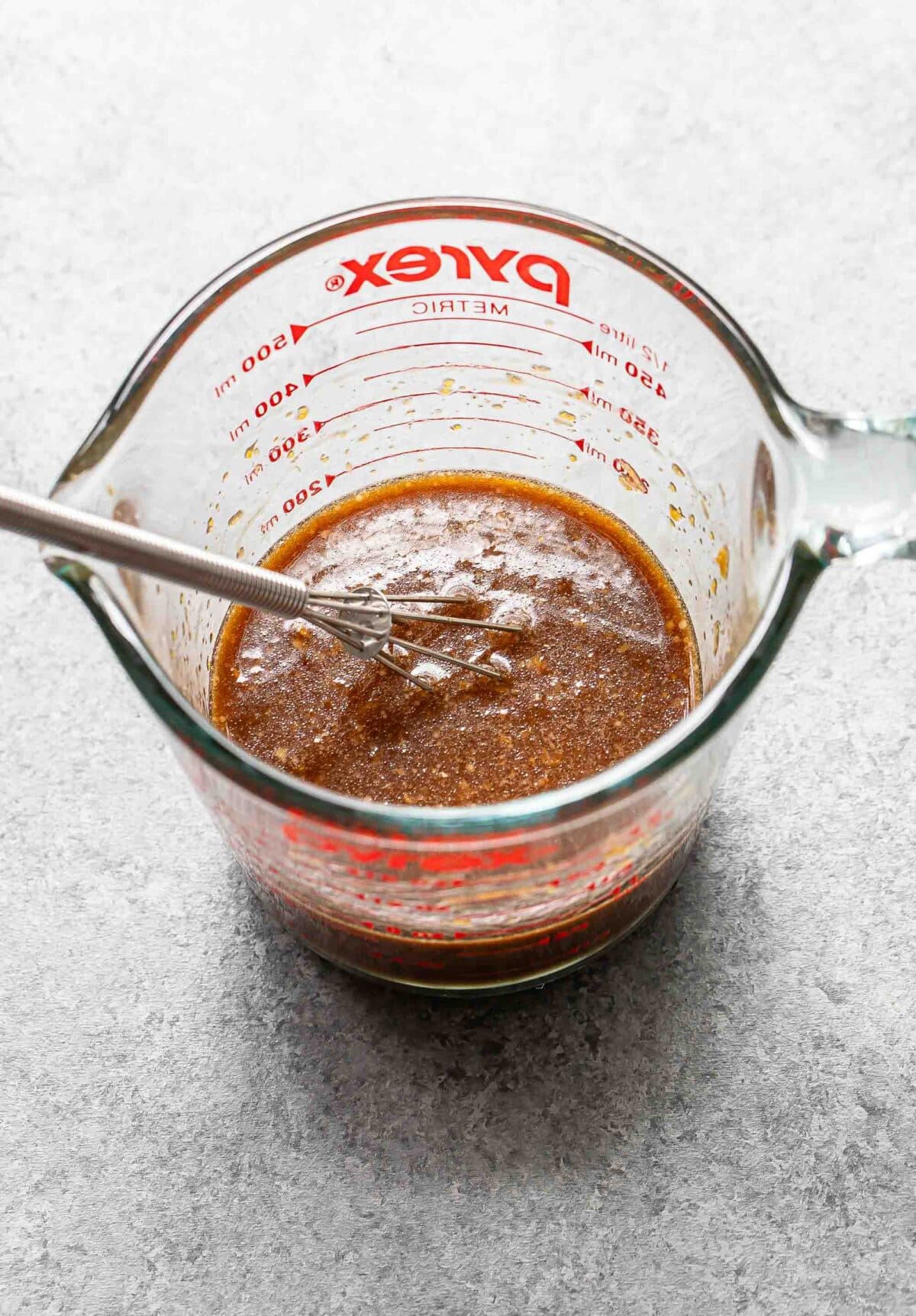 The sauce for Mongolian chicken in a glass measuring cup with a whisk.