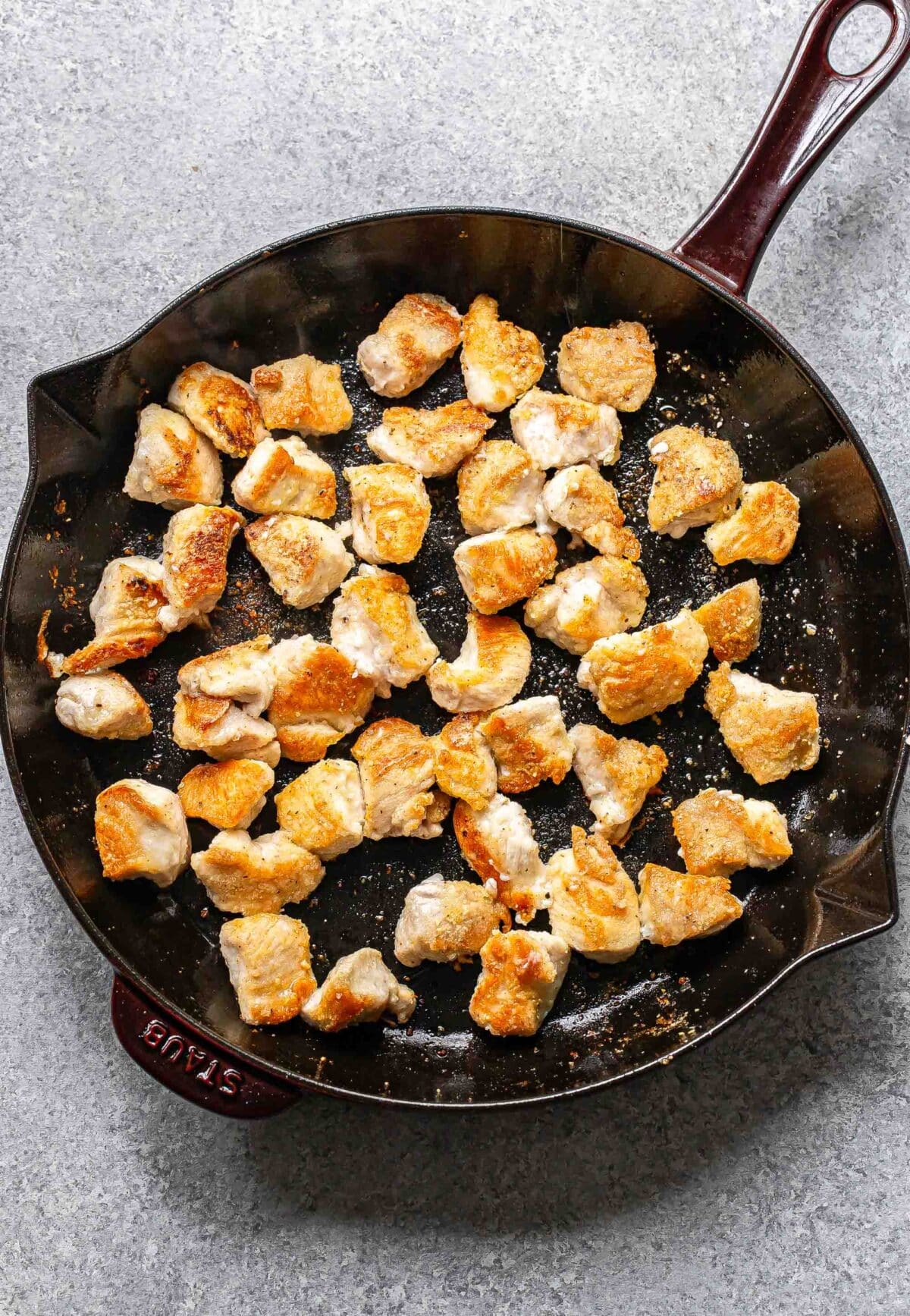 Pieces of crispy cooked chicken in a skillet.