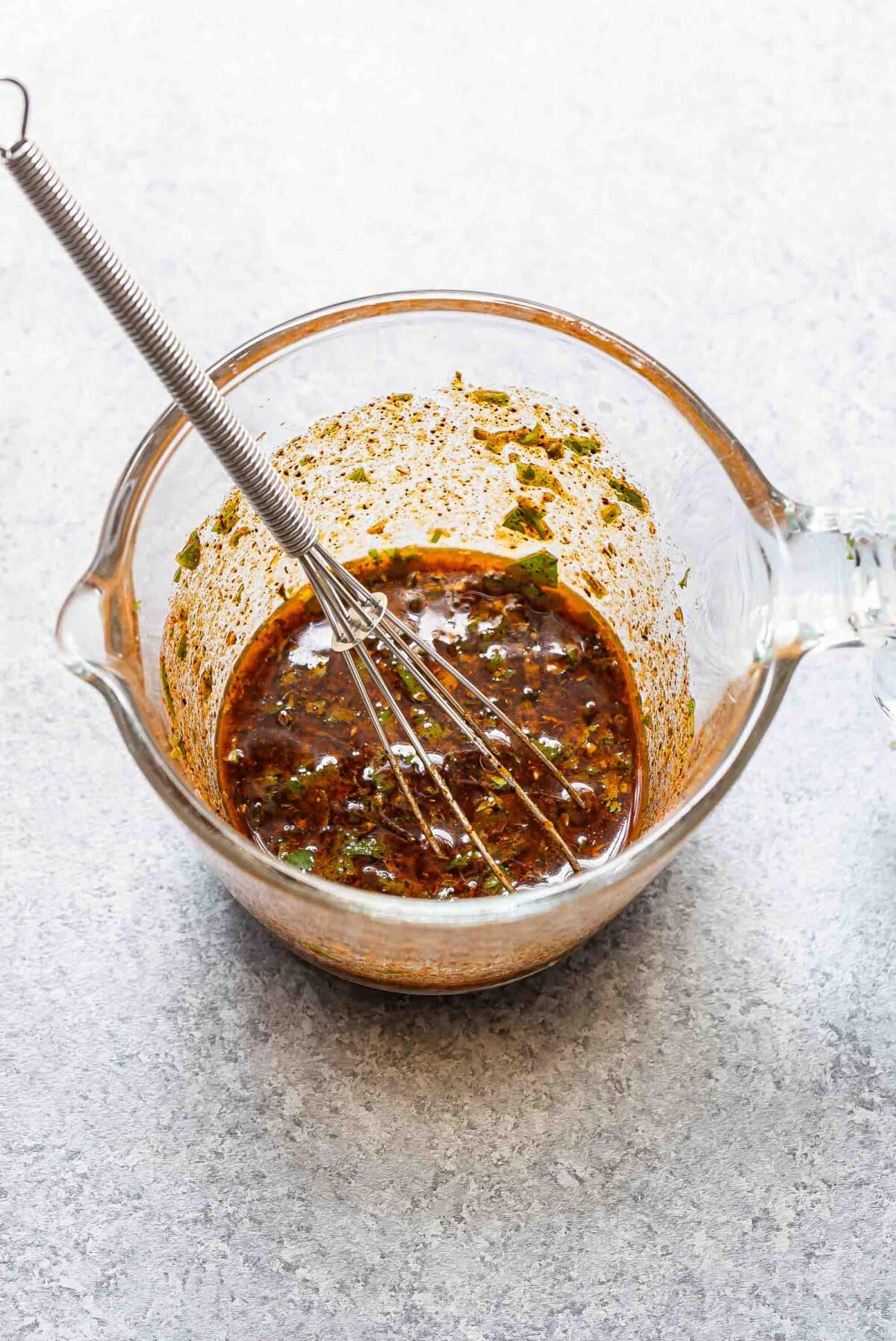 Marinade in a glass measuring cup with a whisk for the southwest chicken.