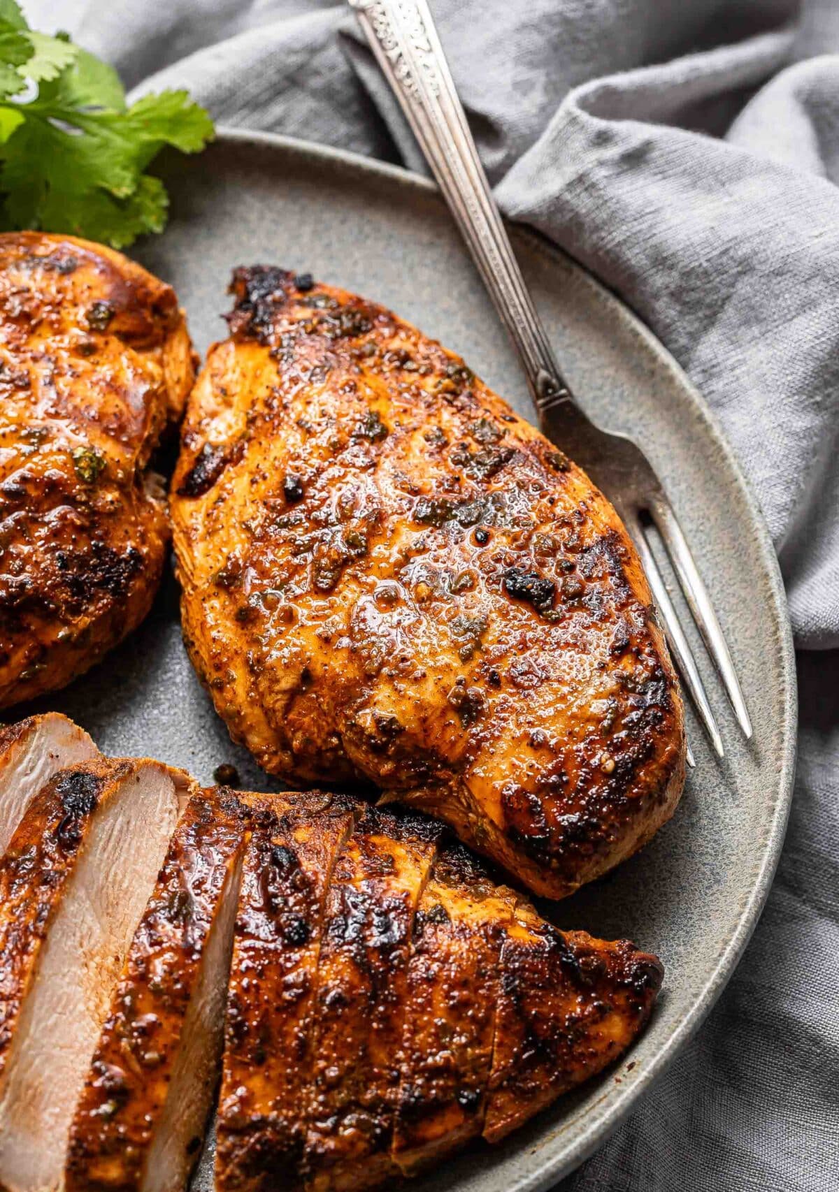 Southwest grilled chicken breast on a gray plate with a fork.