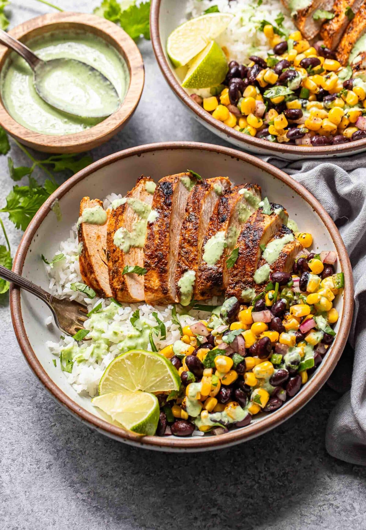 Southwest chicken bowls with black bean corn salsa, grilled chicken, and rice in a white bowl.