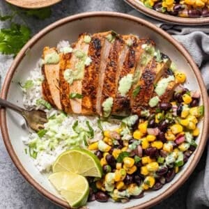 Southwest chicken and rice bowl with black bean corn salsa and cilantro lime dressing in a white bowl with a fork.